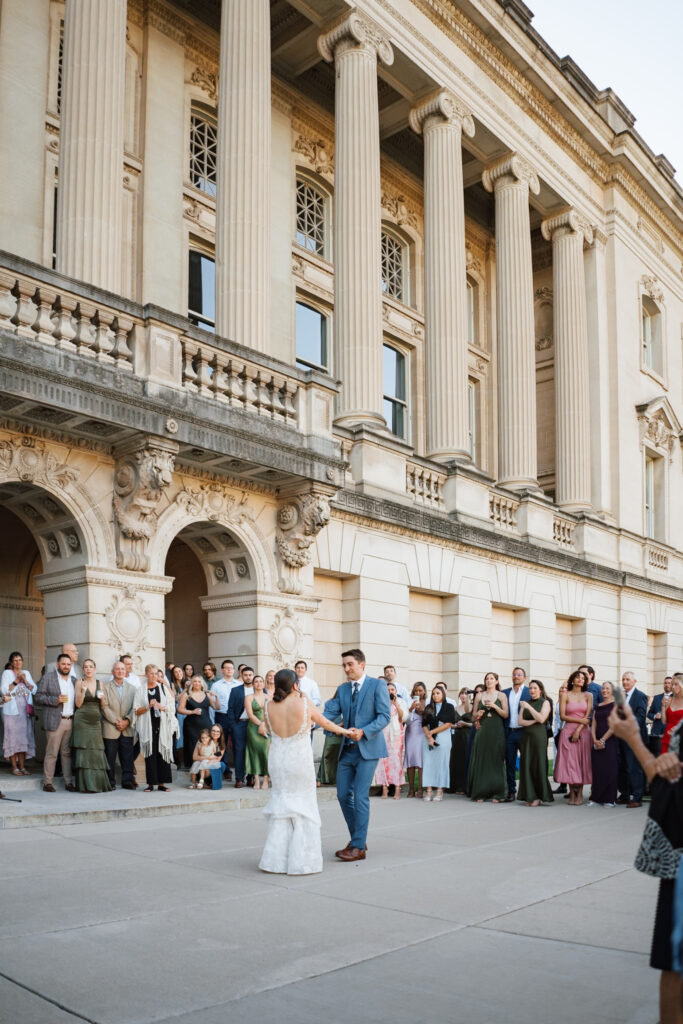 one of the best wedding venues in madison and milwaukee, a bride and groom share a first dance in front of the wisconsin historical society 